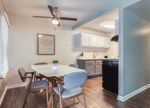 a dining area with a table and chairs and a kitchen in the background at The View Apartments St Charles, St Charles, 60174