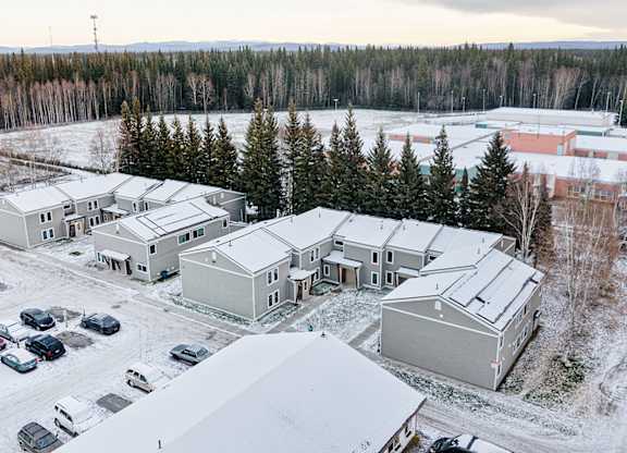 A snowy landscape with a building and cars.
