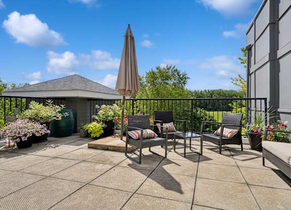 A patio with a table, chairs, and an umbrella.