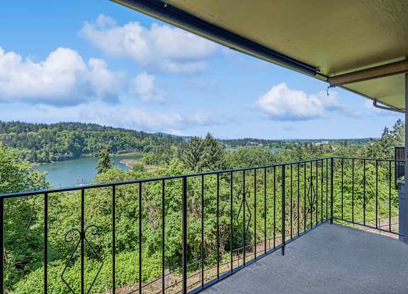 A balcony overlooks a lush green landscape with a body of water in the distance.