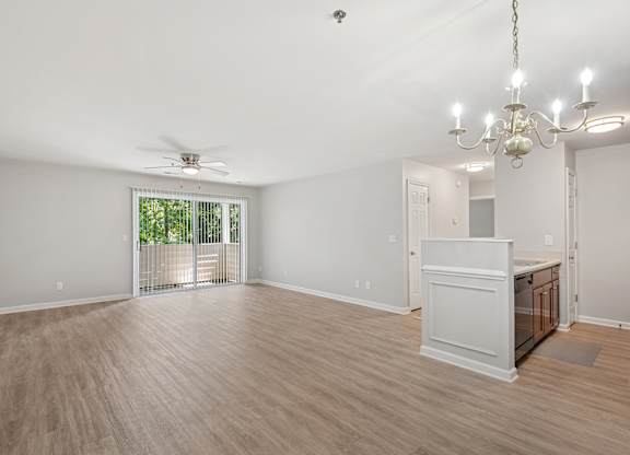 A room with a wooden floor, a ceiling fan, and a chandelier.
