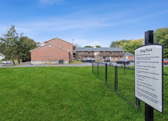 a dog park with a fence and the apartment building in the background at Stonebridge, Ellington, CT, 06029