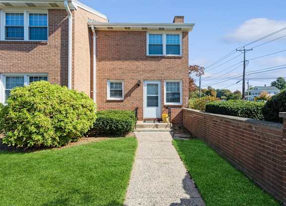 the front of a brick house with a sidewalk and grass