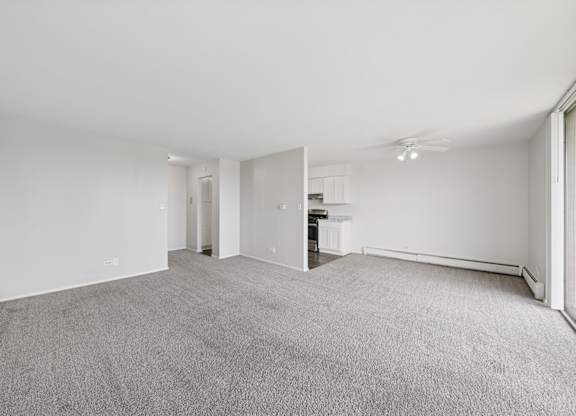 A spacious, empty room with grey carpeting and white walls.