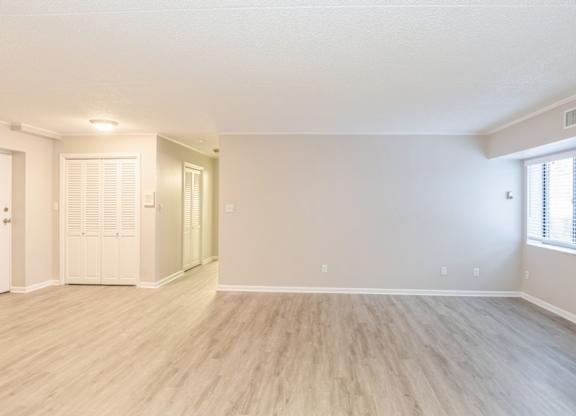 A spacious living room with wooden flooring and white walls