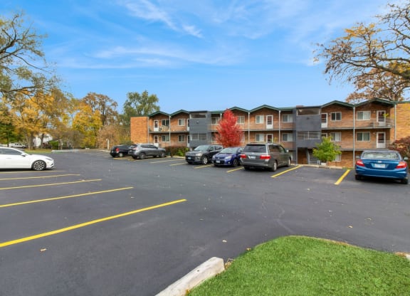 an empty parking lot with cars in front of an apartment building at River Oaks, North Aurora, IL