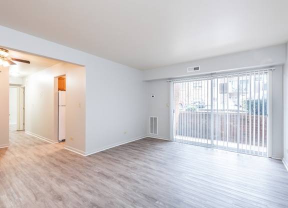 A spacious room with a sliding glass door leading to a balcony.