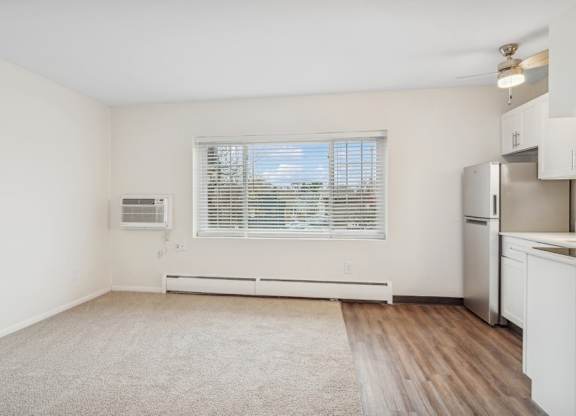 A kitchen with white cabinets and a window with blinds.