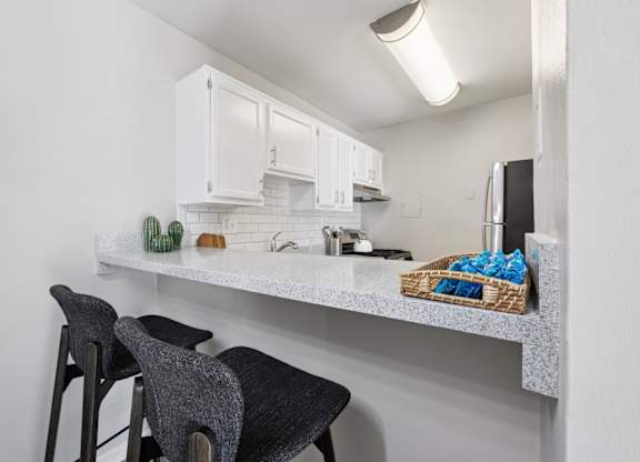 A kitchen with white cabinets and a counter with a basket of blue cloths on it.