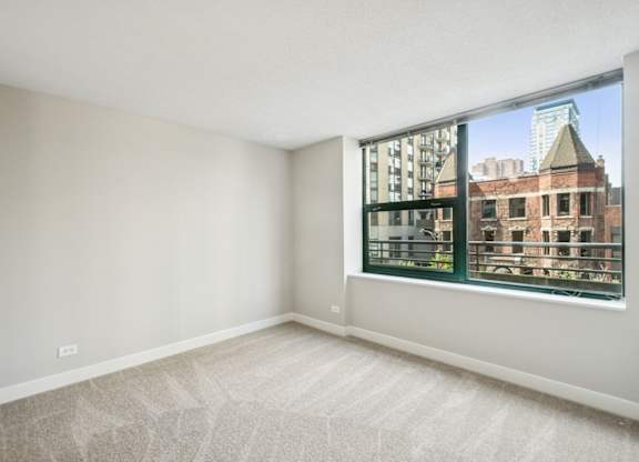 Empty room with a large window overlooking a cityscape.