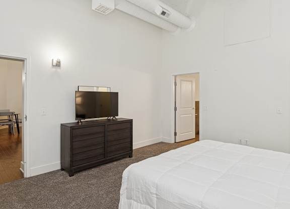 A bedroom with a bed, a dresser, and a television.