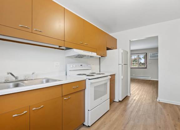 A kitchen with white appliances and wooden cabinets.