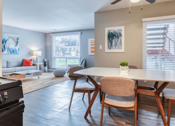 a dining area with a table and chairs and a living room in the background at The View Apartments St Charles, St Charles, IL, 60174