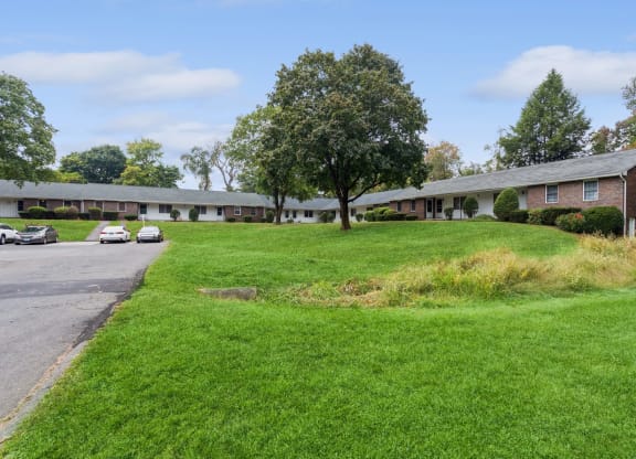 the front of a building with a green lawn and a parking lot