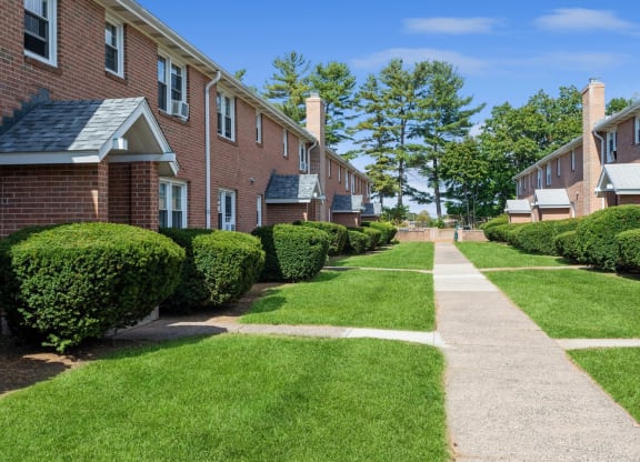 a sidewalk in front of a row of brick apartment building