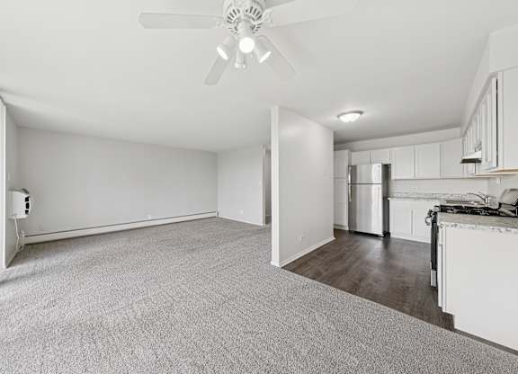 A spacious room with a ceiling fan and carpeted floor.