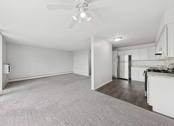 A spacious room with a ceiling fan and carpeted floor.