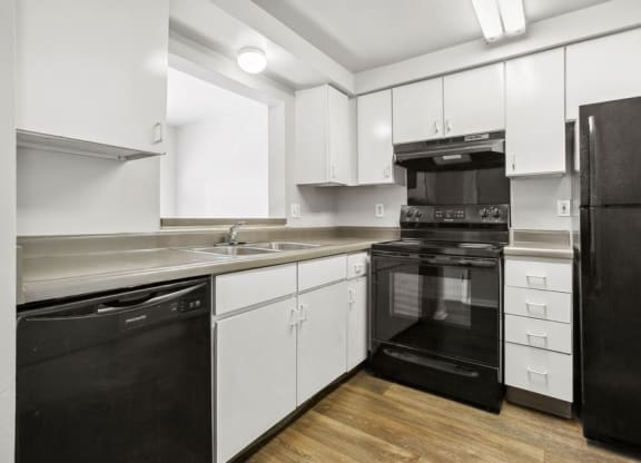 a kitchen with white cabinets and black appliancesat Mason Street Townhomes, Grand Rapids, Michigan