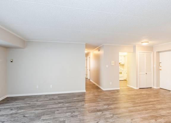 A spacious room with wooden flooring and white walls.