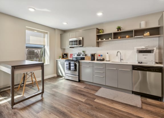 an open kitchen with stainless steel appliances and a table at The Rowe, Grand Rapids, 49503