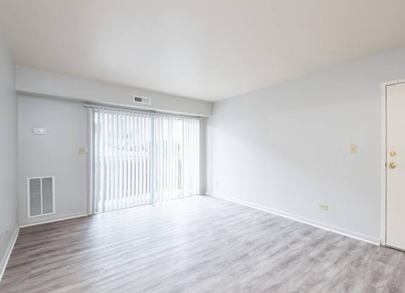 A large, empty room with a sliding door and wooden flooring.