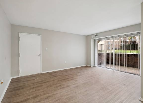 A living room with a white door and a window with a metal grate.