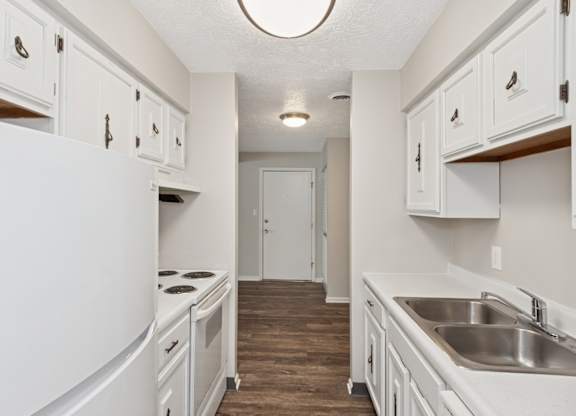 A kitchen with white cabinets and a white refrigerator.