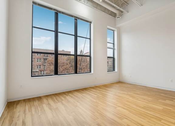 A room with wooden floors and large windows overlooking a cityscape.