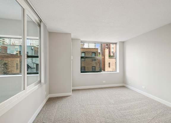 A spacious room with a carpeted floor and large windows.