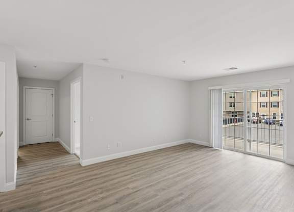A spacious room with wooden flooring and white walls.