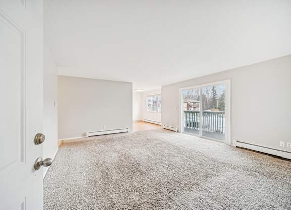 A room with a carpeted floor and a door on the left side.