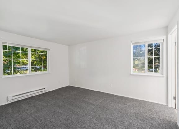 a spacious room with two windows, carpet flooring, and white walls at Murrayhill Park, Beaverton Oregon