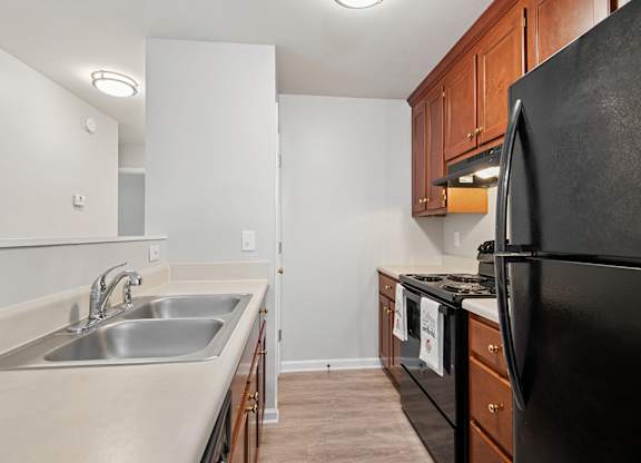 A kitchen with a black refrigerator and wooden cabinets