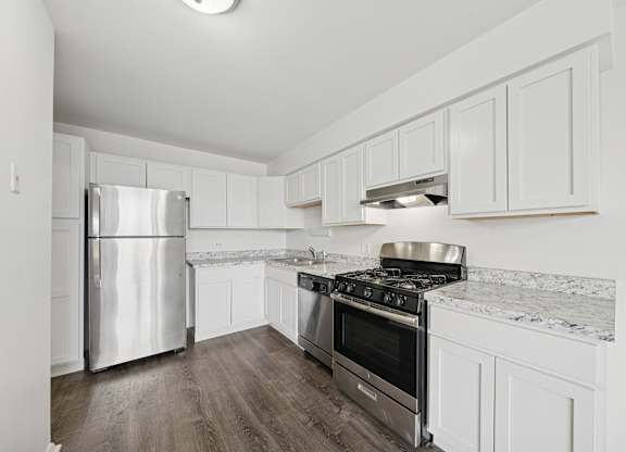 A kitchen with white cabinets and a stainless steel refrigerator.