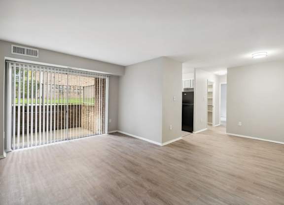 A living room with a sliding glass door and a black refrigerator.