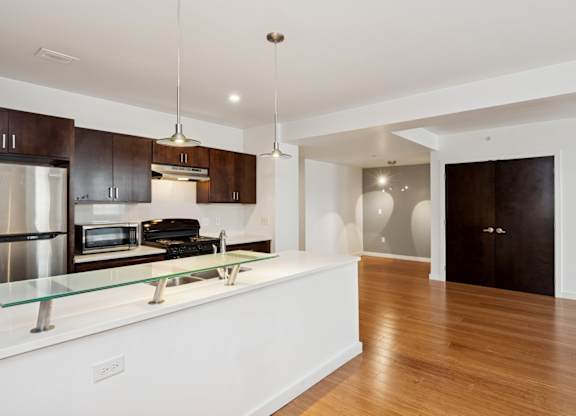A modern kitchen with wooden floors and white walls.