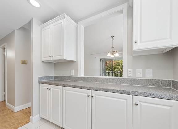 A kitchen with white cabinets and a grey countertop.