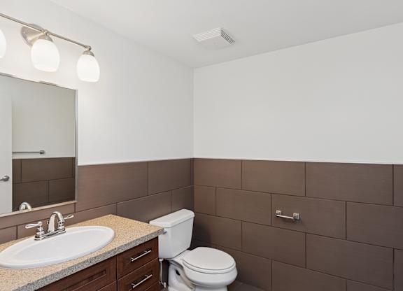 A bathroom with brown tiles and a white toilet.