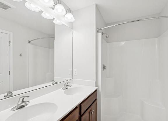 A white bathroom with a sink and mirror.