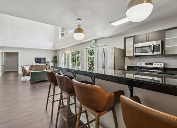 A modern kitchen with brown chairs and a black countertop.
