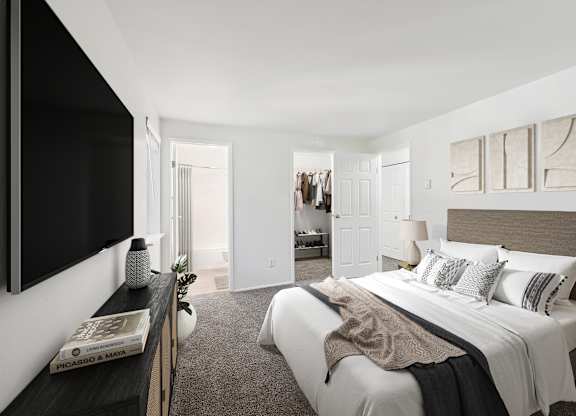 A bedroom with a large bed and a flat screen TV mounted on the wall.