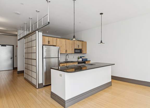 A modern kitchen with wooden floors and a white island.