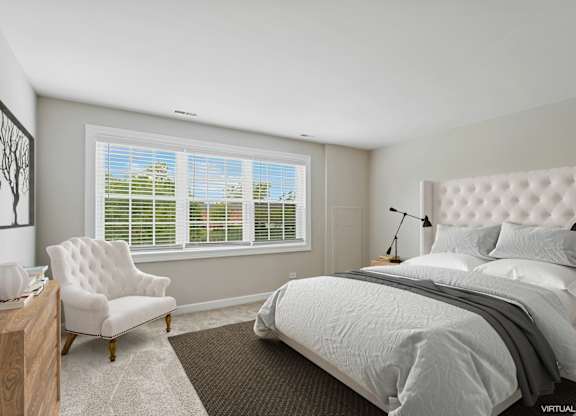 A bedroom with a large bed, a chair, and a window with blinds.