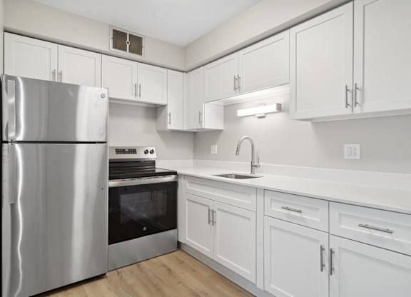 A modern kitchen with white cabinets and stainless steel appliances.