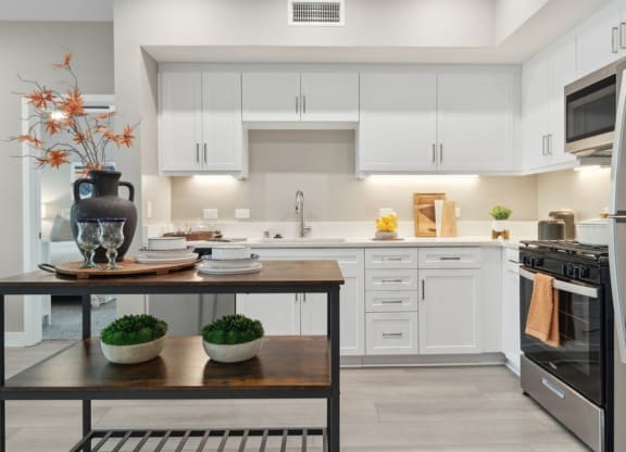 a kitchen with white cabinets and an island at Arrive Temecula