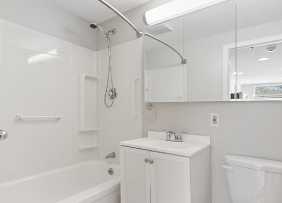 A white bathroom with a tub, sink, and mirror.