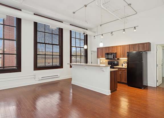 A kitchen with a black refrigerator and wooden cabinets.