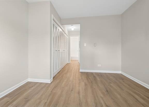 A long hallway with wood floors and white walls.