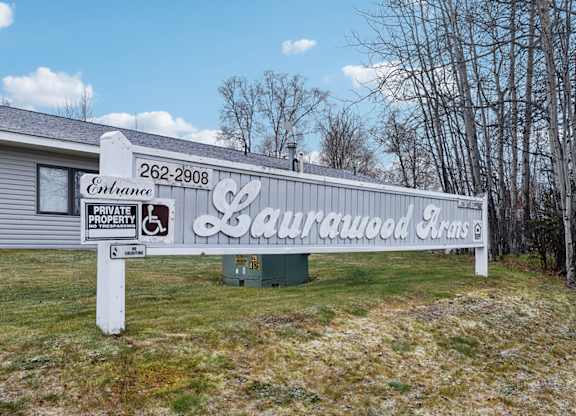 A sign for Laurawood Farms stands in front of a building.