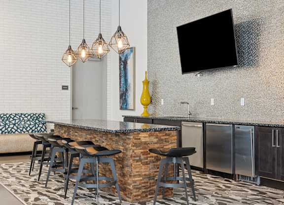 A modern bar area with a stone counter and stools.